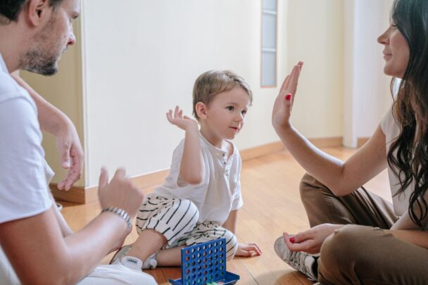 Vader en moeder spelen een spelletje met een jongetje. Moeder geeft de jongen een high five.