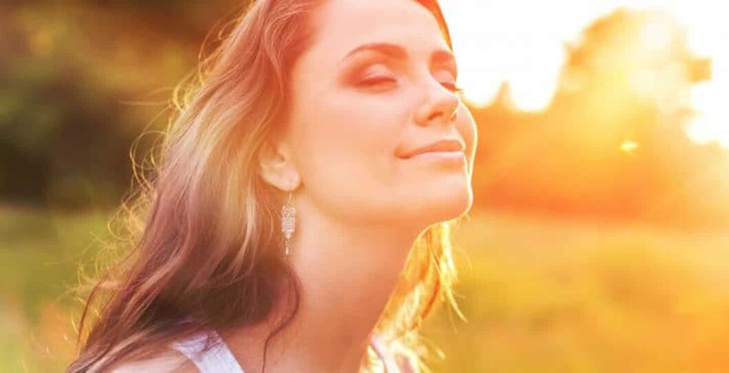 vrouw kijkt in de zon met gesloten ogen en oogt tevreden en blij|Young woman on field under sunset light|een houten tafel met twee dumbbells