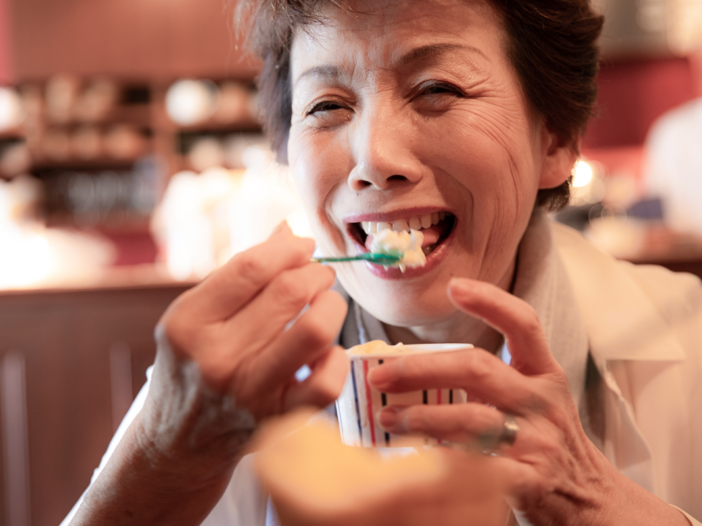 Oudere vrouw eet een ijsje.