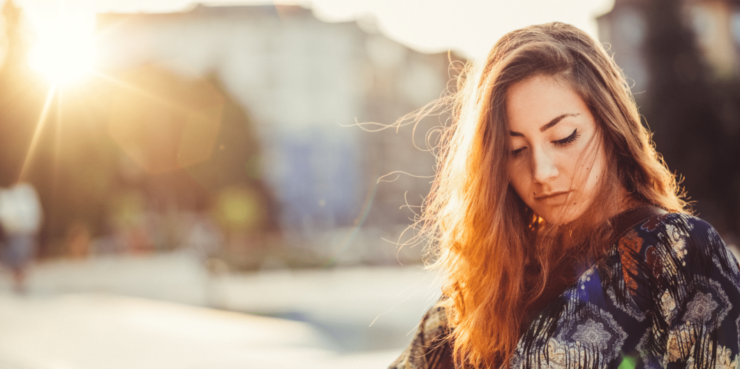 vrouw zit buiten in de zon en kijkt naar beneden|vrouw zit in de auto met zonnebril en kijkt gestresst