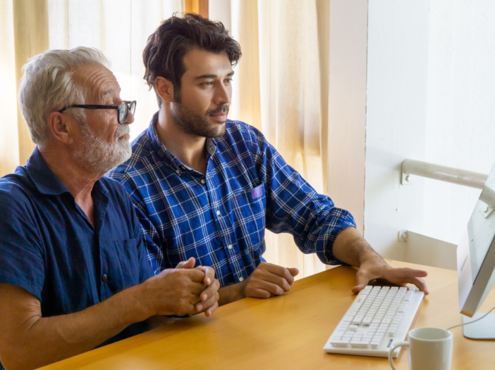 Jongere en oudere man achter de computer