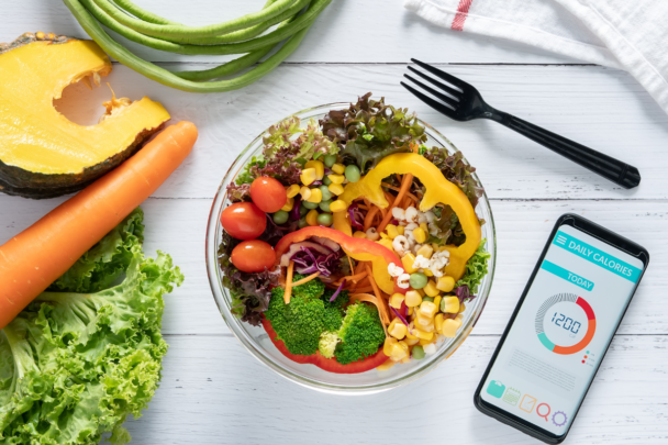Een schaal met kleurrijke groentes op tafel. En een telefoon met een meet app.