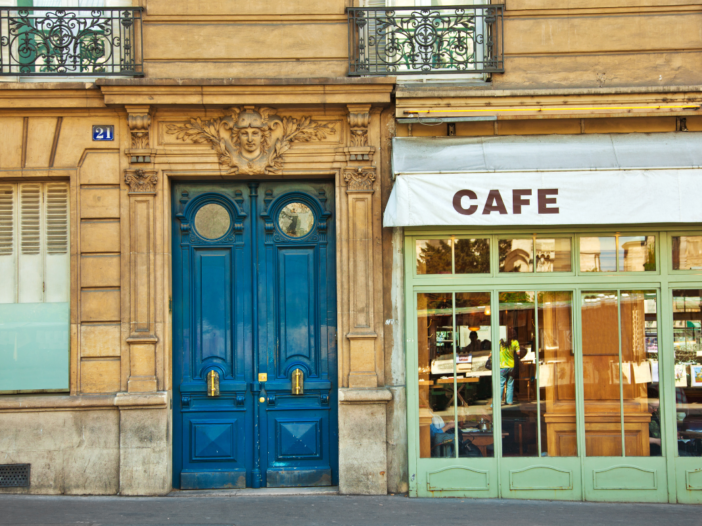 Oud artistiek café met een mooie blauwe deur en een luifel.