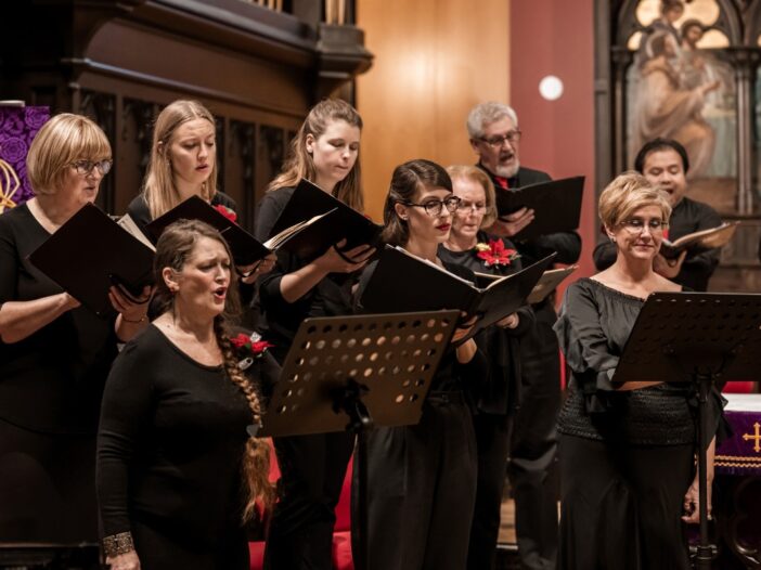 In dit koor staan mannen en vrouwen te zingen uit volle borst. Ze hebben allemaal zwarte kleren aan en staan in een kerk.