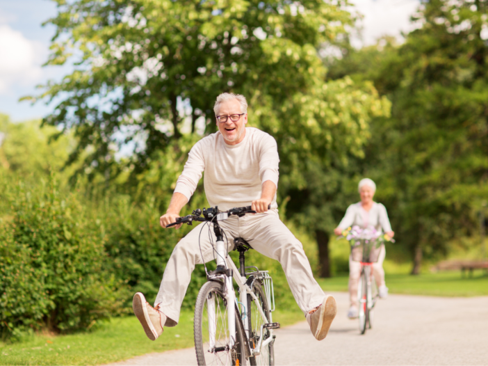 Een senioren man die op zijn fiets zit. Achter hem fietst iemand anders van de fietsclub.