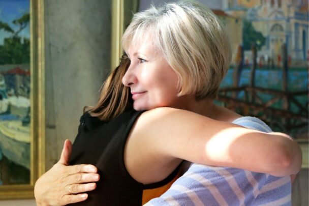 Blonde vrouw geeft een andere vrouw een knuffel. Een knuffel om de ander te steunen.