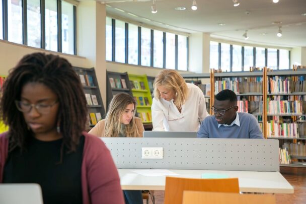 Meerdere mensen werken aan tafel achter hun laptop in een bibliotheek