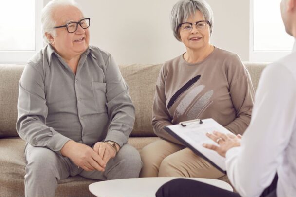 Oudere dame en heer in gesprek met iemand in een wit overhemd