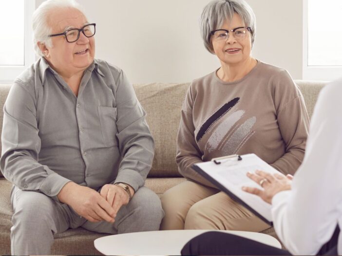 Oudere dame en heer in gesprek met iemand in een wit overhemd