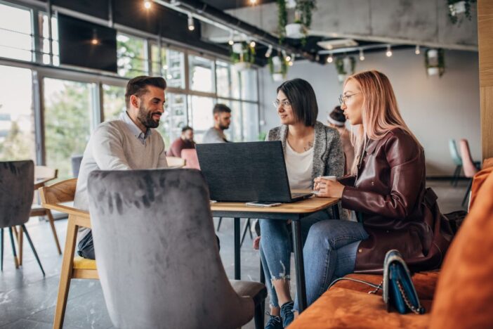 Drie mensen maken in een café gebruik van een laptop