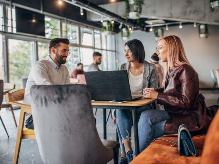 Drie mensen maken in een café gebruik van een laptop