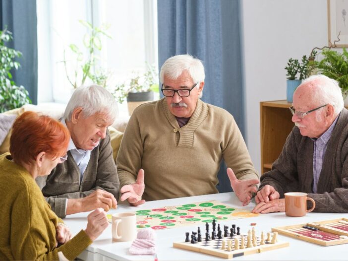 Vier ouderen spelen een bordspel aan tafel