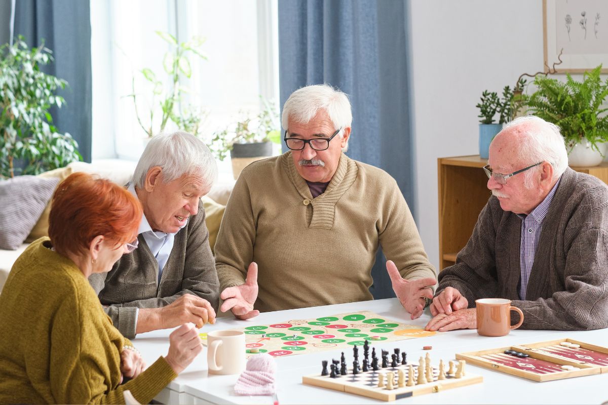 Vier ouderen spelen een bordspel aan tafel