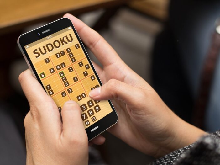 Iemand speelt sudoku puzzel op zijn mobiel