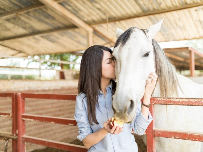 Vrouw geeft een paard een kus op de wang