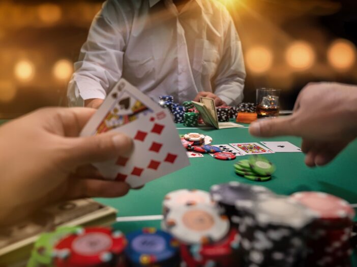 Ingezoomde foto van een pokertafel met 3 spelers, kaarten en pokerfiches