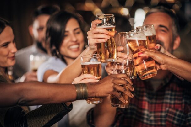 Groepje mensen proost met glazen bier in een kroeg