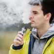 Man met gele jas is buiten aan het vapen