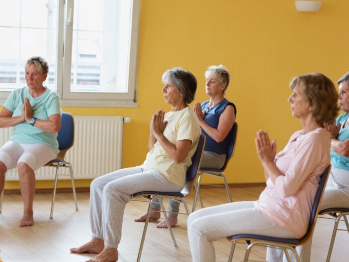 Groepje oudere vrouwen doet aan stoelyoga.