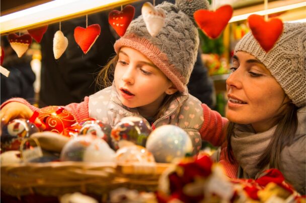 Meisje en moeder zijn samen op een kerstmarkt naar mooie spullen aan het kijken.