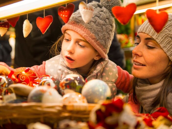 Meisje en moeder zijn samen op een kerstmarkt naar mooie spullen aan het kijken.