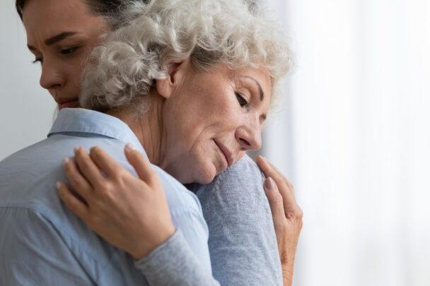 Een jongere en een oudere vrouw geven elkaar een knuffel.