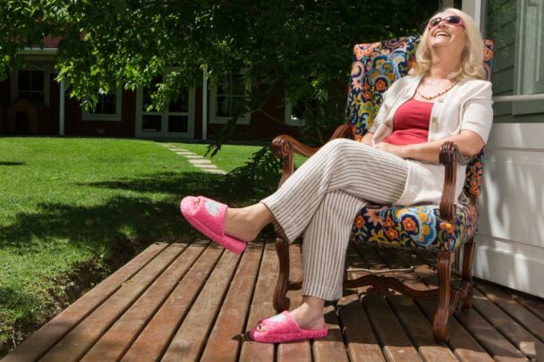 Vrouw zit ontspannen in haar tuin in de zon te genieten.