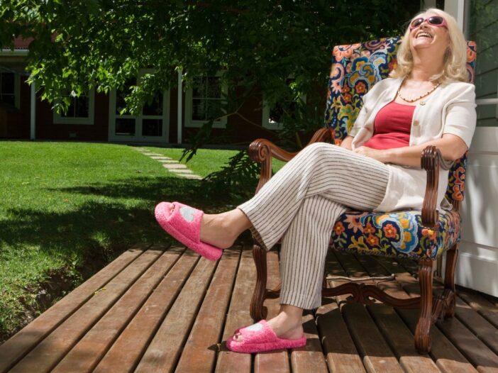 Vrouw zit ontspannen in haar tuin in de zon te genieten.