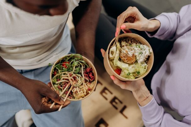 Bovenaanzicht van een man en vrouw die samen een gezonde salade met noedels eten.