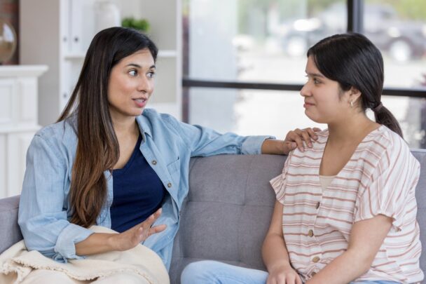 Twee vrouwen zitten op de bank en zijn met elkaar in gesprek.