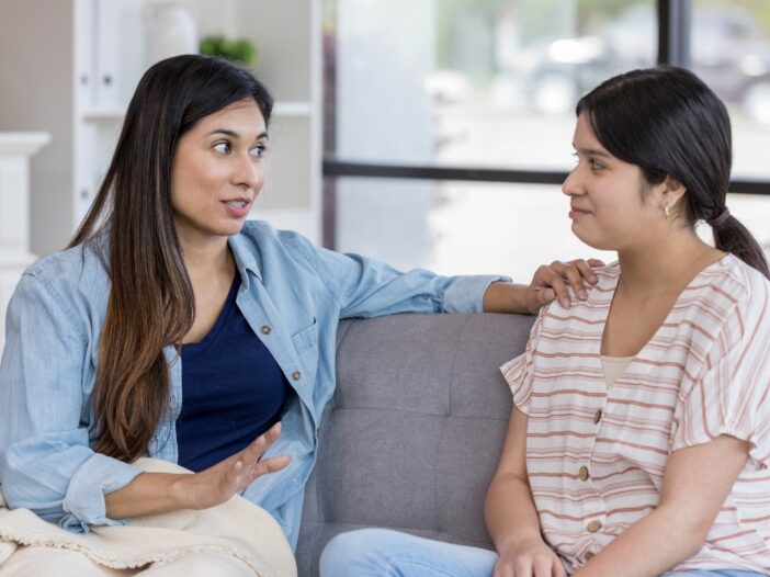 Twee vrouwen zitten op de bank en zijn met elkaar in gesprek.