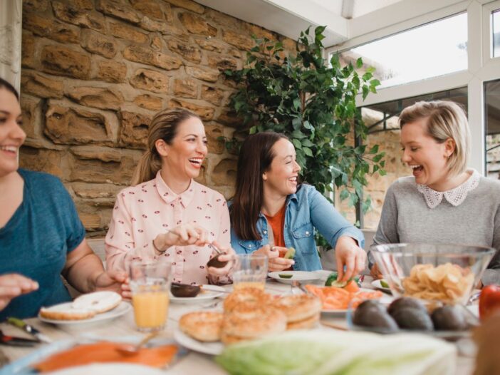 Vier vriendinnen zitten aan tafel te kletsen en lachen.