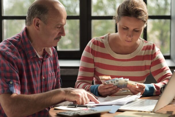 Man en vrouw zitten samen aan tafel en bekijken papierwerk en contact geld.