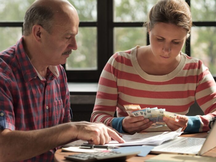 Man en vrouw zitten samen aan tafel en bekijken papierwerk en contact geld.