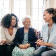 Oudere vrouw zit met twee vrouwen op de bank.